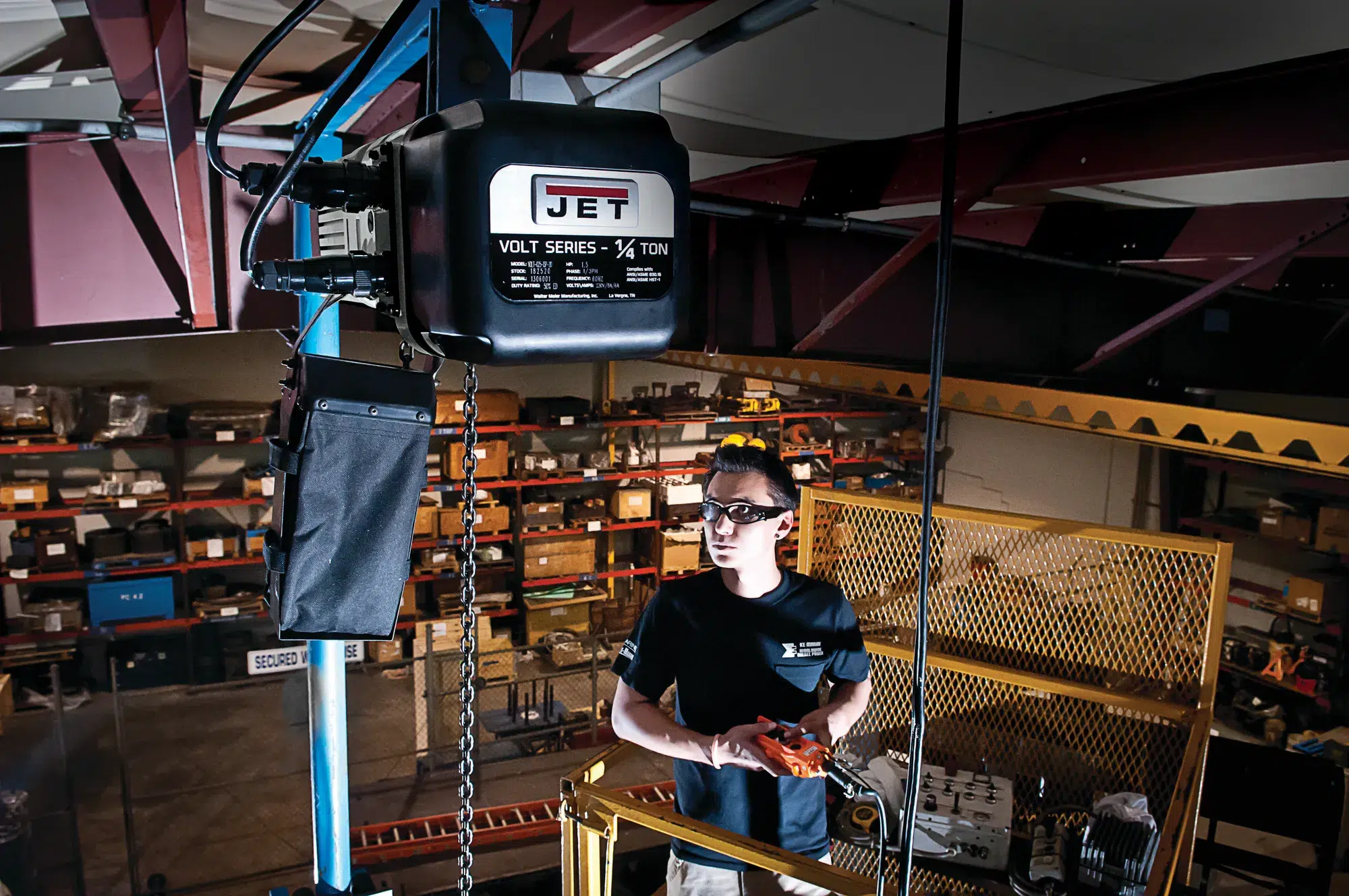 A man stands in front of a lift, showcasing JET Brand's reliable lifting systems for various industrial applications.
