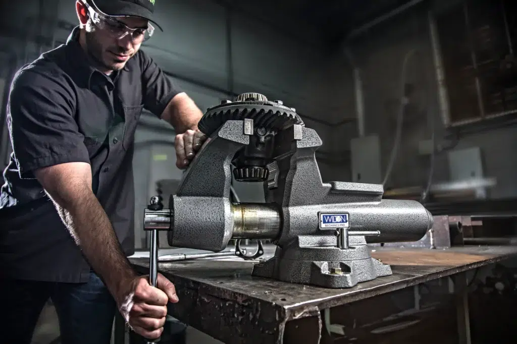 A man operates a machine in a workshop, showcasing Wilton's high-quality work holding solutions for precision tasks.